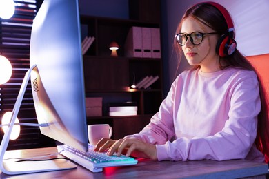 Photo of Girl in headphones using computer keyboard at table indoors