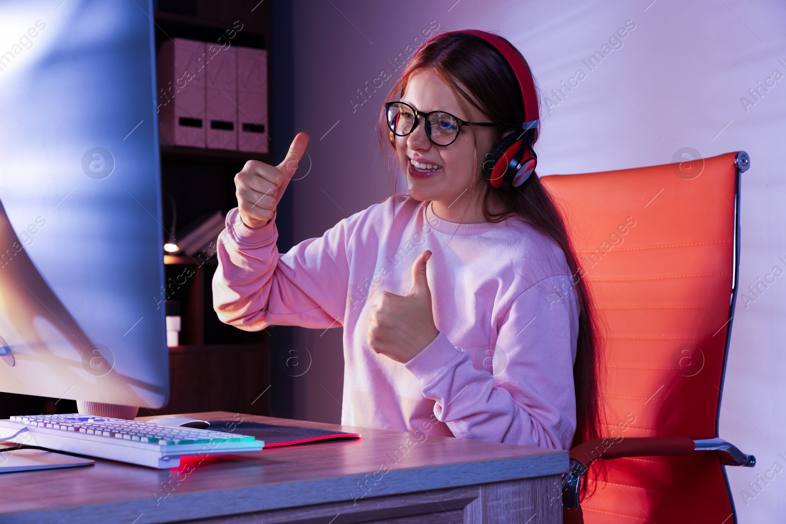 Photo of Happy girl playing video game with keyboard at table indoors