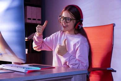 Happy girl playing video game with keyboard at table indoors