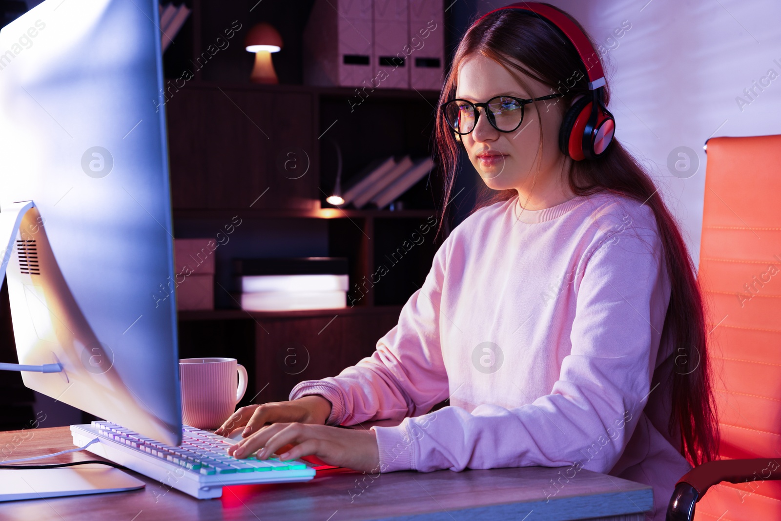 Photo of Girl in headphones using computer keyboard at table indoors