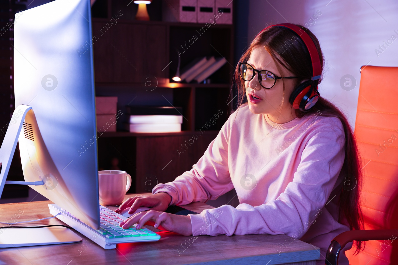 Photo of Girl in headphones using computer keyboard at table indoors