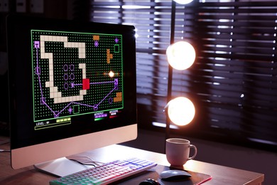 Photo of Computer keyboard, monitor, cup and mouse on table indoors. Space for text