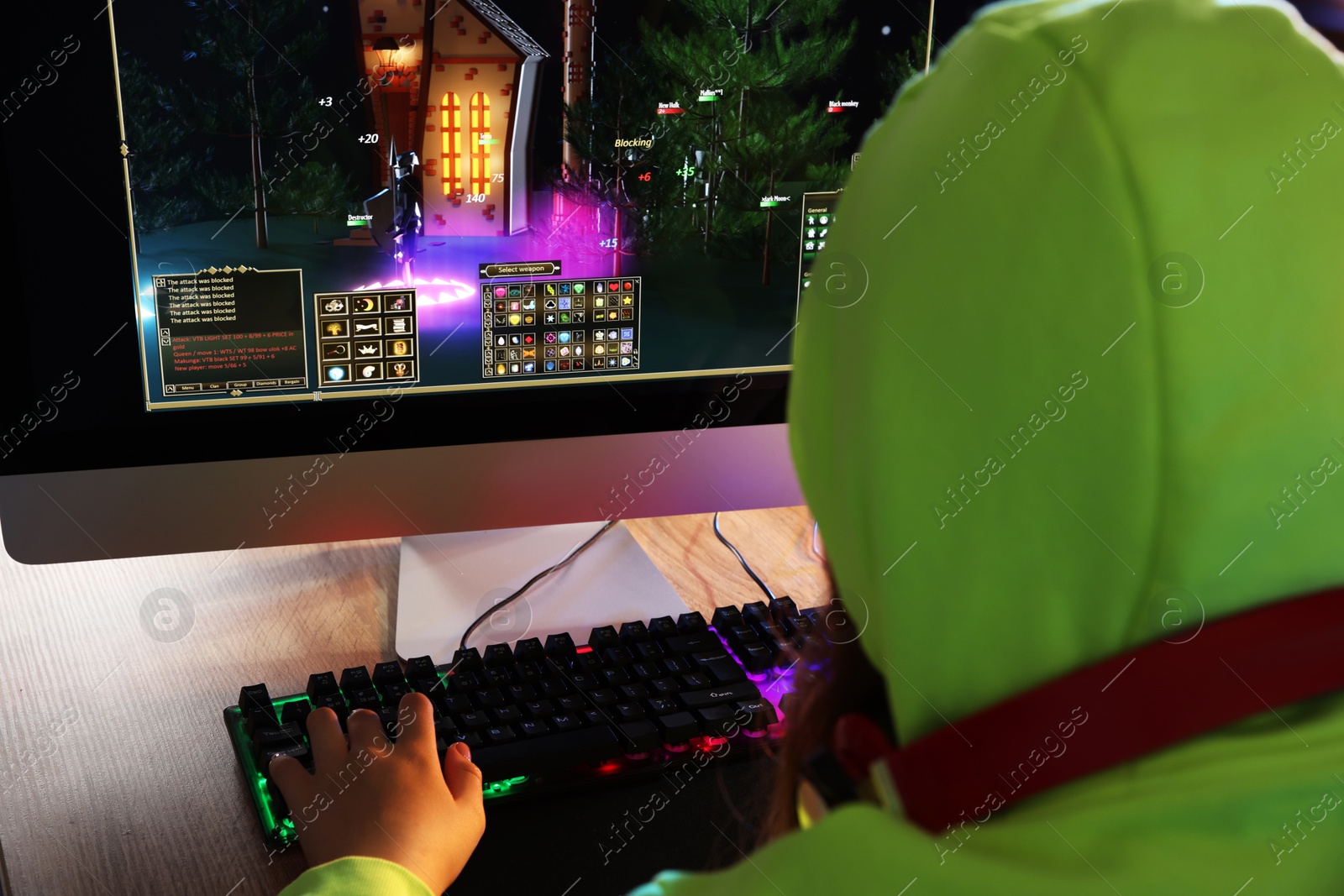 Photo of Girl playing video game with keyboard at table, back view