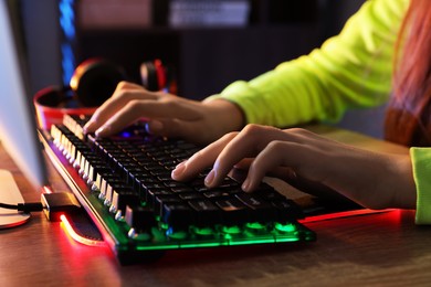 Photo of Girl using computer keyboard at wooden table indoors, closeup