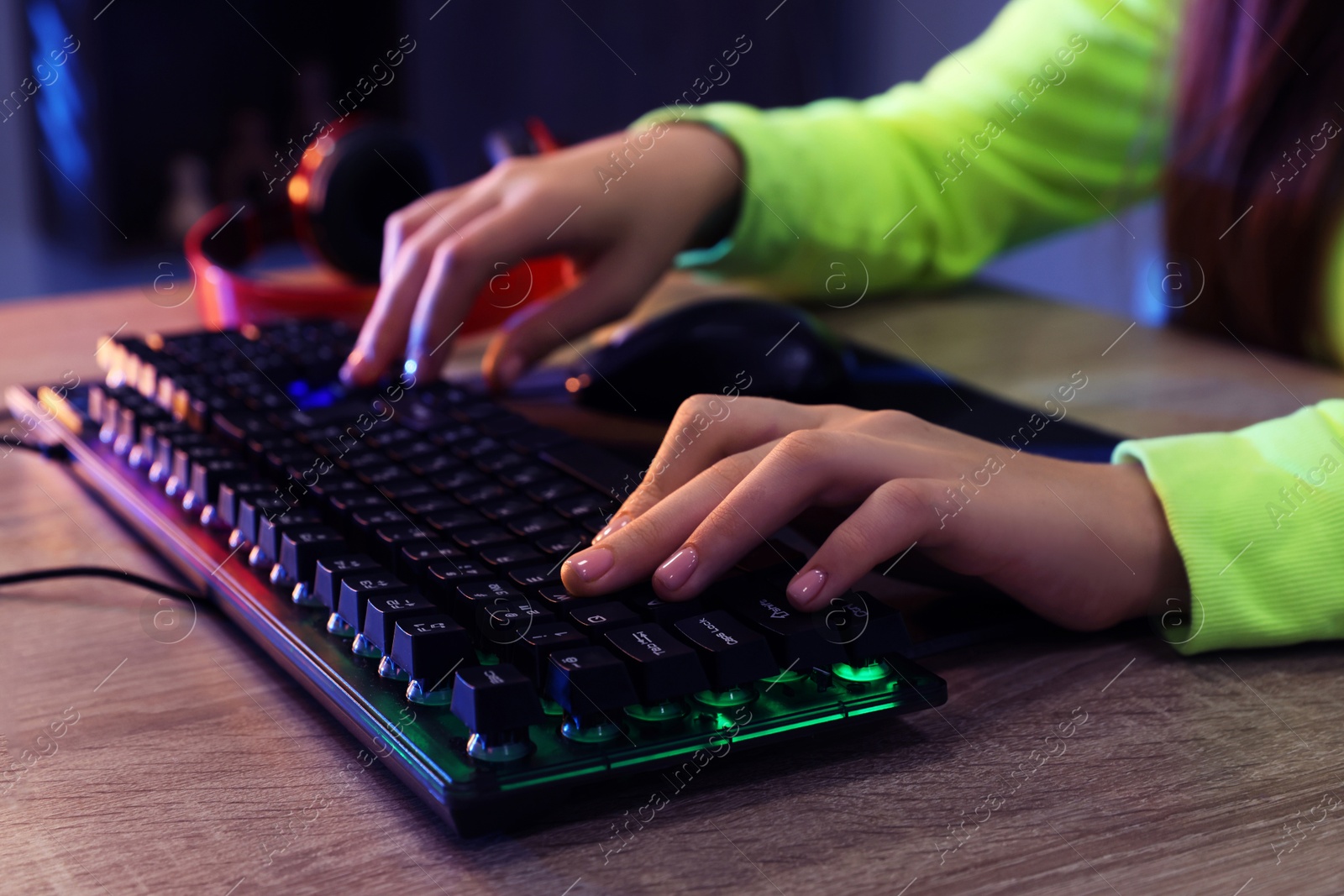 Photo of Girl using computer keyboard at wooden table indoors, closeup