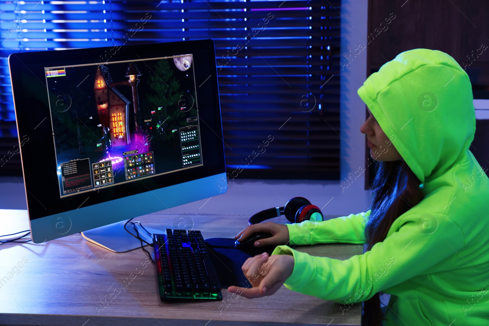 Photo of Girl playing video game with keyboard and mouse at table indoors