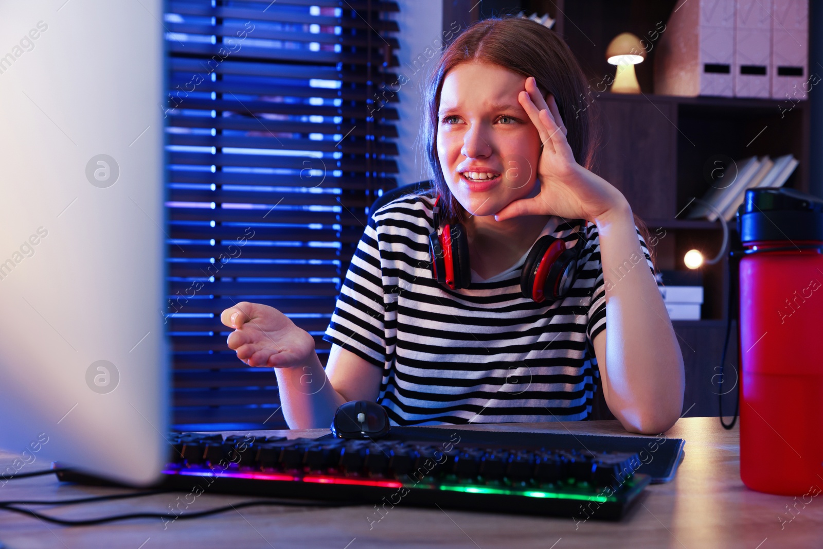 Photo of Emotional girl playing video game with keyboard and mouse at table indoors