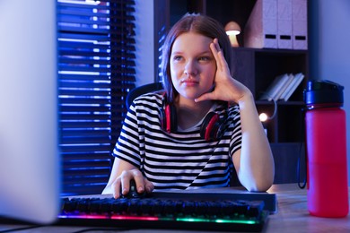 Photo of Girl playing video game with keyboard and mouse at table indoors