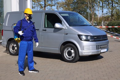 Photo of Pest control worker with spray tank outdoors