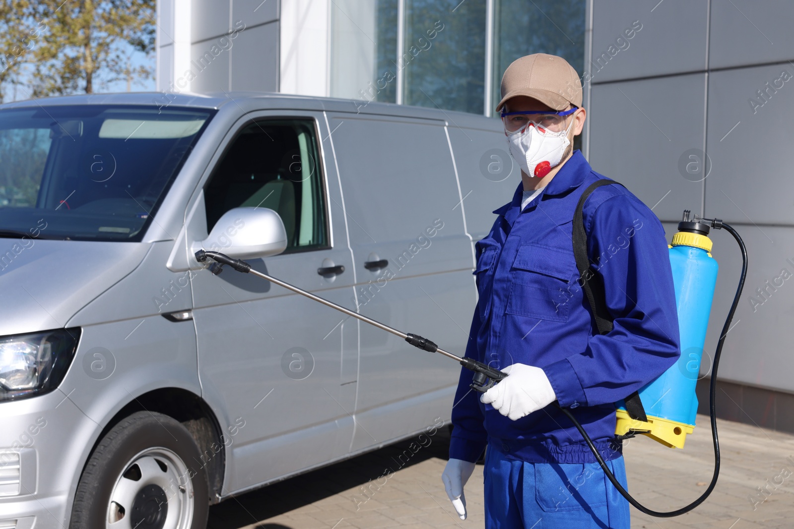 Photo of Pest control worker with spray tank outdoors