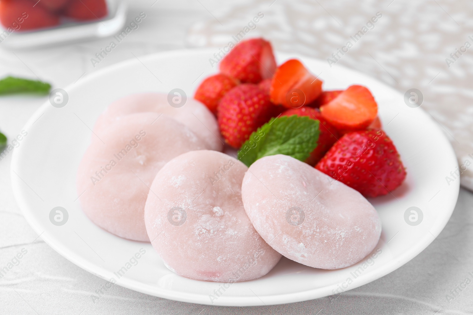 Photo of Delicious mochi and strawberries on white table, closeup