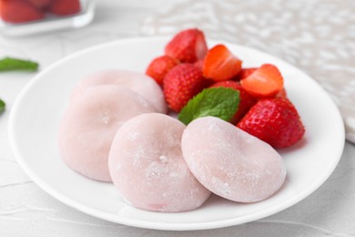 Photo of Delicious mochi and strawberries on white table, closeup