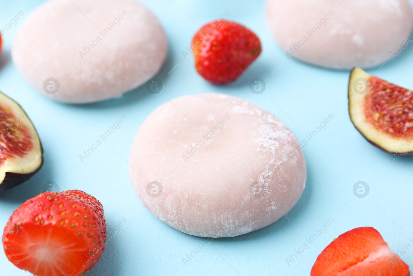 Photo of Delicious mochi, strawberries and figs on light blue background, closeup