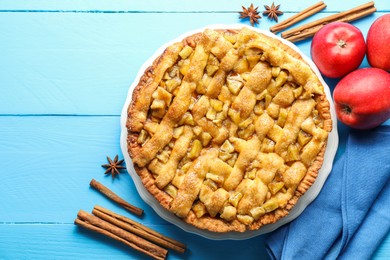 Photo of Homemade apple pie and ingredients on light blue wooden table, flat lay. Space for text