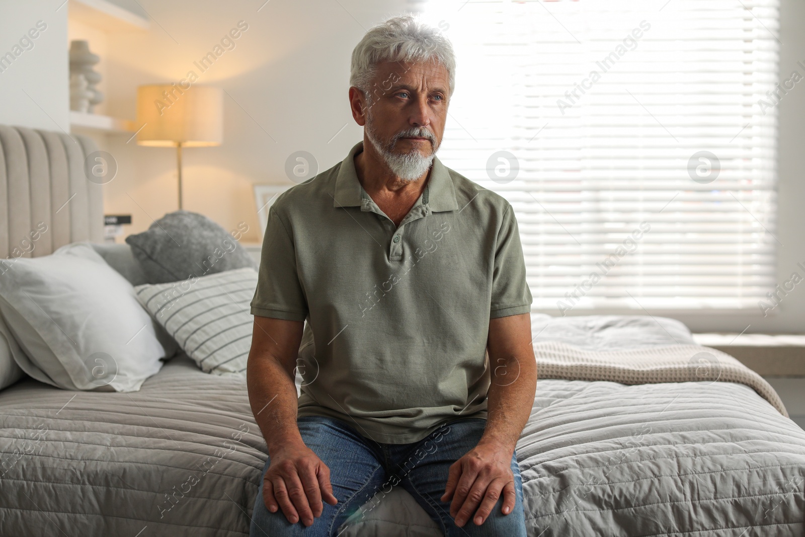 Photo of Lonely senior man sitting on bed at home