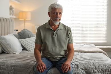 Photo of Lonely senior man sitting on bed at home