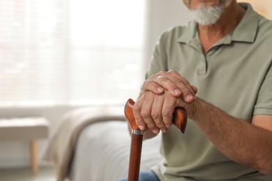 Photo of Lonely senior man with walking cane at home, closeup. Space for text