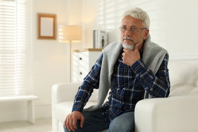 Photo of Lonely senior man sitting on sofa at home. Space for text