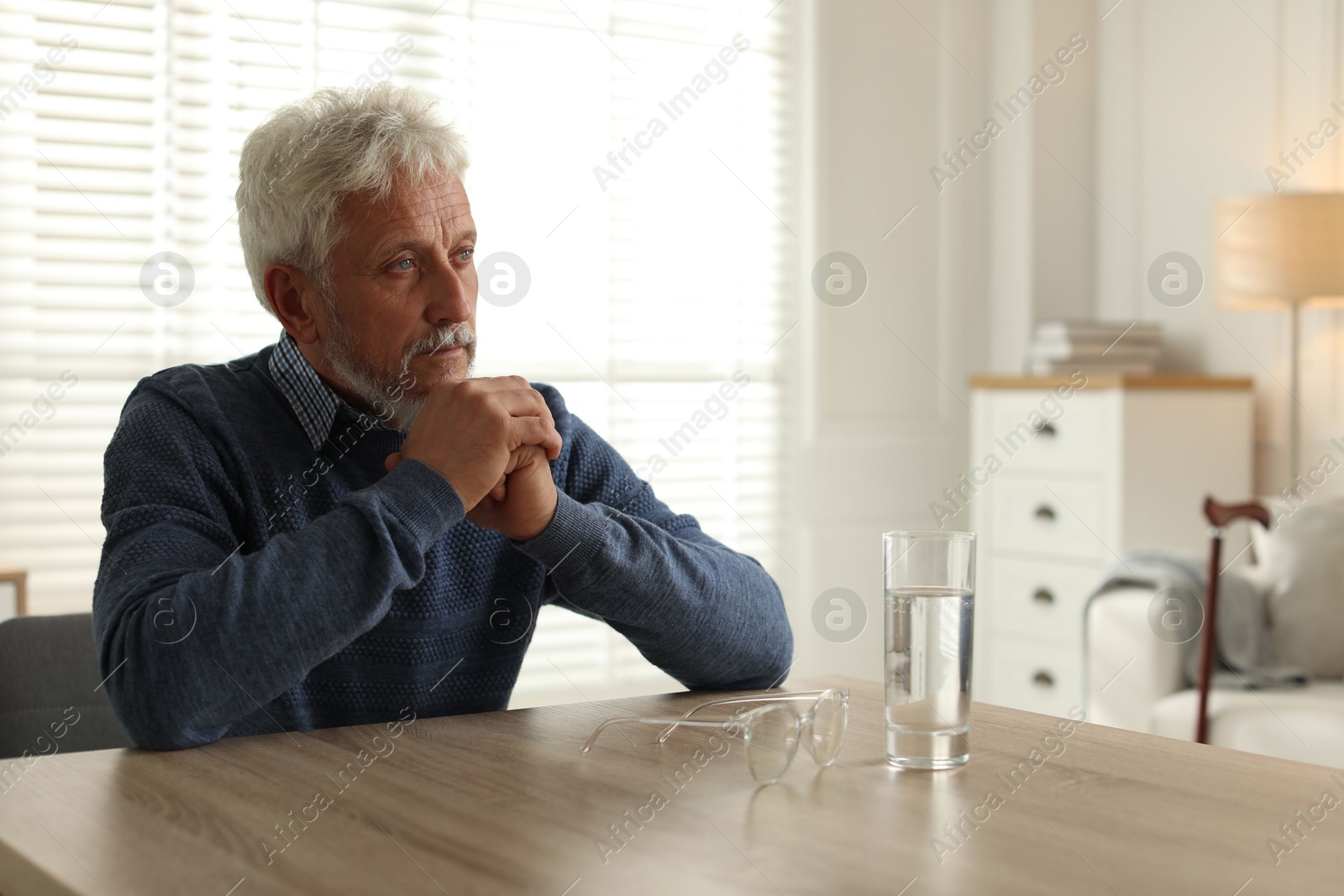 Photo of Lonely senior man sitting at table in room