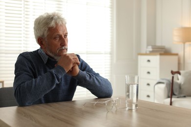 Photo of Lonely senior man sitting at table in room