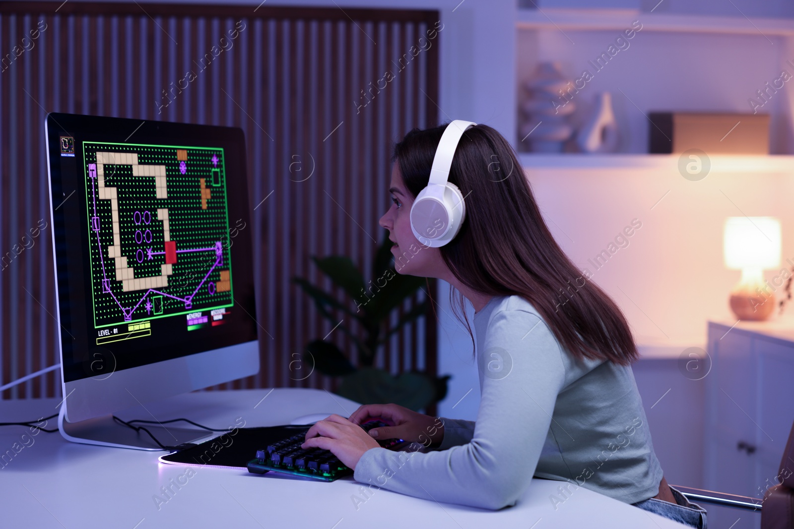 Photo of Woman in headphones playing video game with keyboard at table indoors