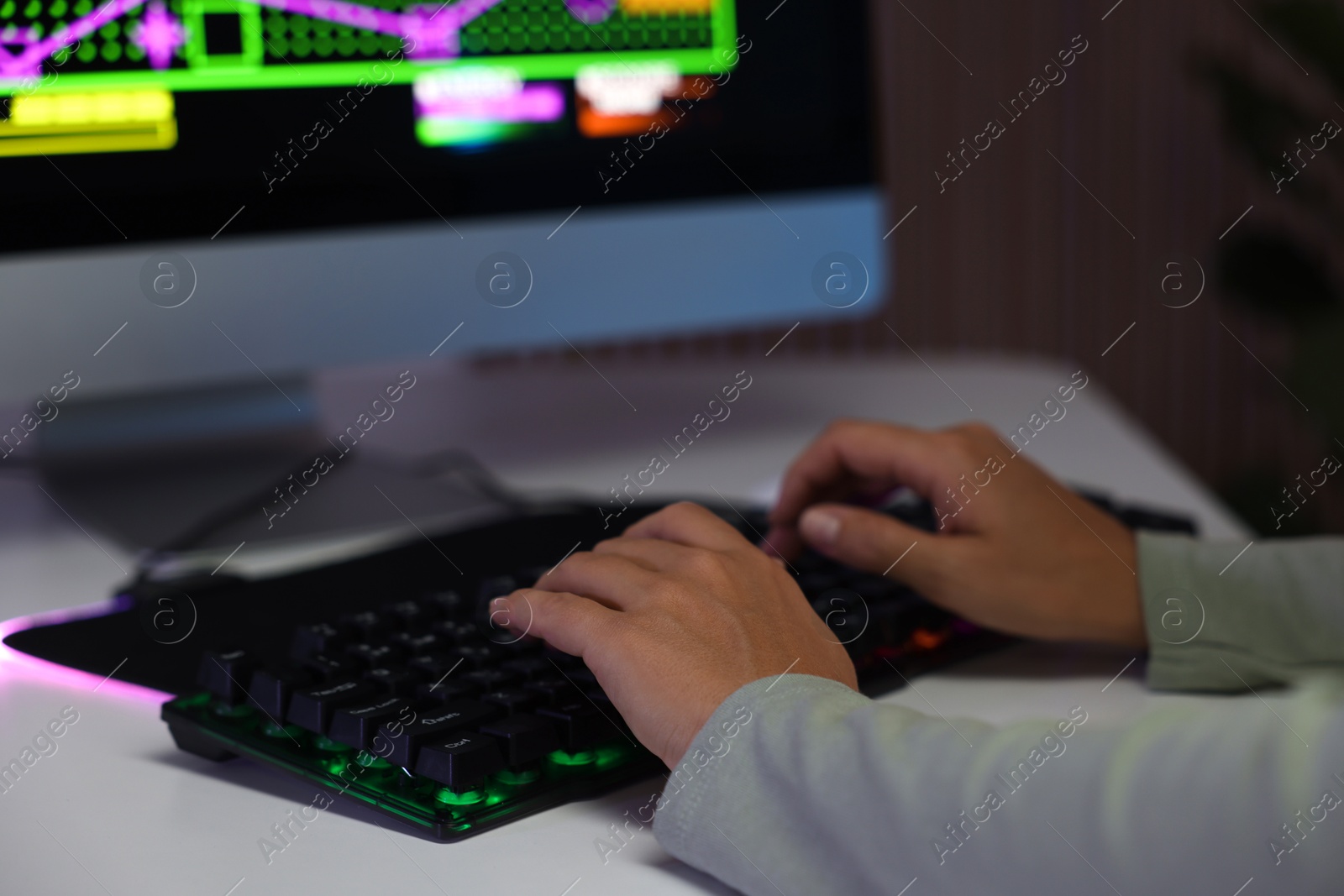 Photo of Woman using computer keyboard at white table indoors, closeup