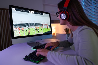 Photo of Woman in headphones playing video game with keyboard at table indoors