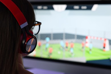 Woman in headphones watching game live stream indoors, closeup