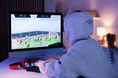 Photo of Woman playing video game with keyboard at table indoors