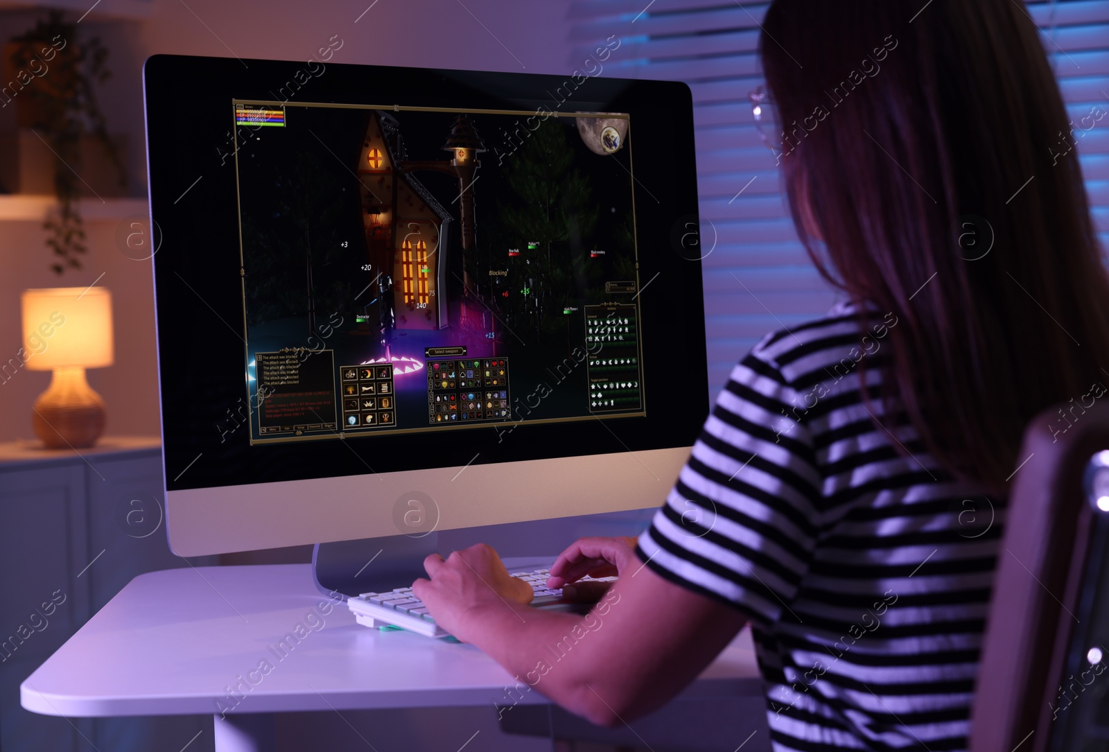 Photo of Woman playing video game with keyboard at table indoors, back view