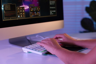 Photo of Woman playing video game with keyboard at white table indoors, closeup