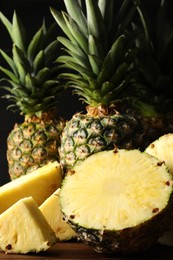 Photo of Whole and cut ripe pineapples on wooden table