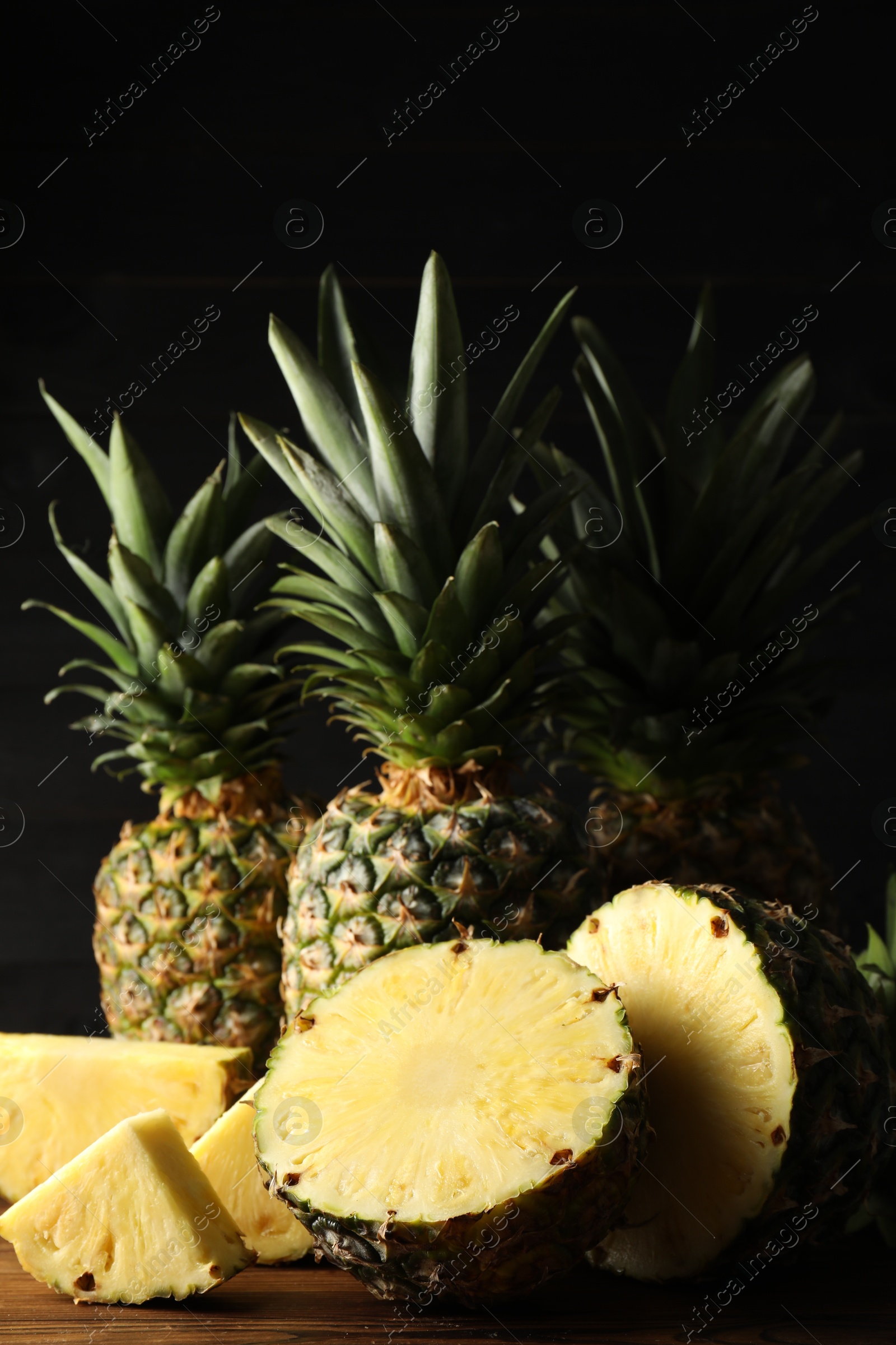 Photo of Whole and cut ripe pineapples on wooden table