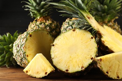 Photo of Whole and cut ripe pineapples on wooden table