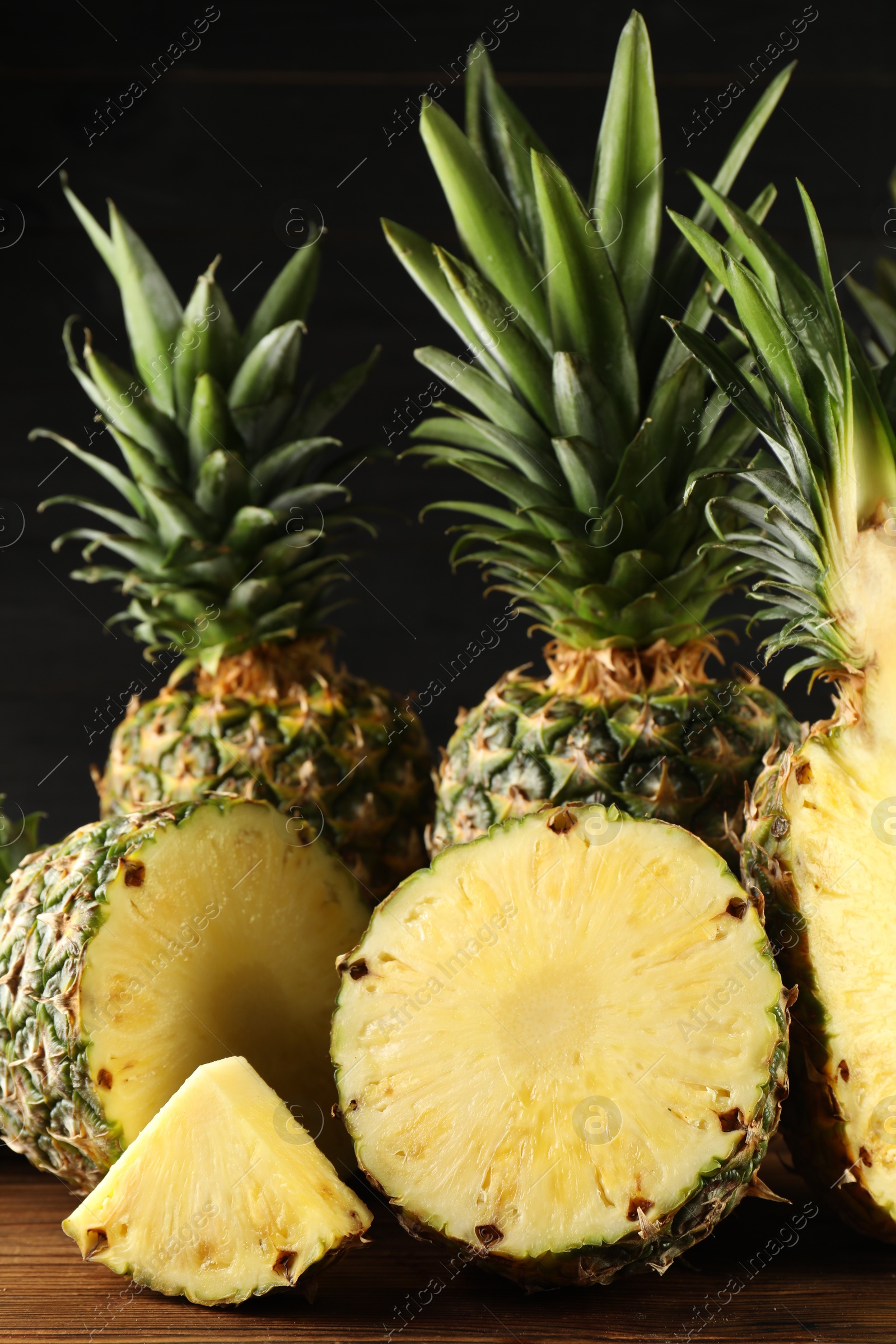 Photo of Whole and cut ripe pineapples on wooden table