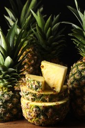 Whole and cut ripe pineapples on wooden table