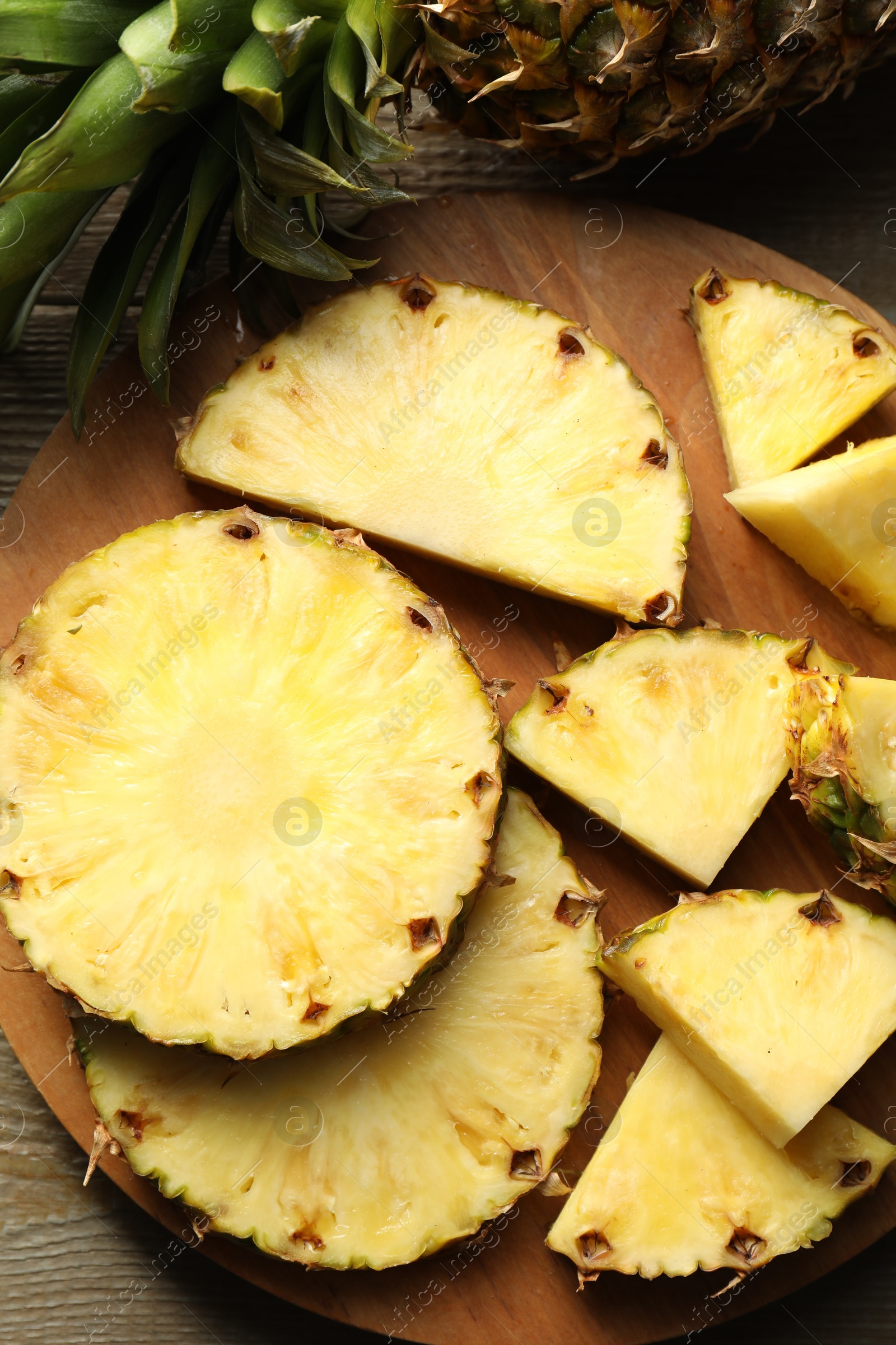 Photo of Slices of fresh ripe pineapple on wooden table, top view