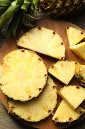 Photo of Slices of fresh ripe pineapple on wooden table, top view