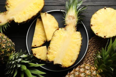 Photo of Fresh ripe pineapples on black wooden table, top view