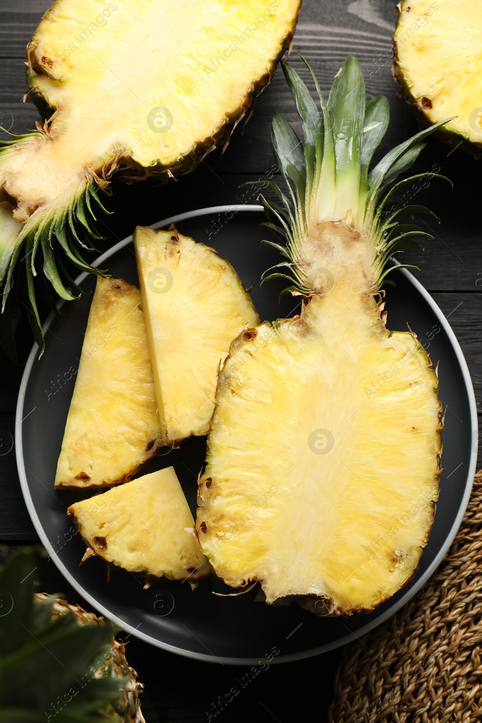 Photo of Fresh ripe pineapples on black wooden table, top view