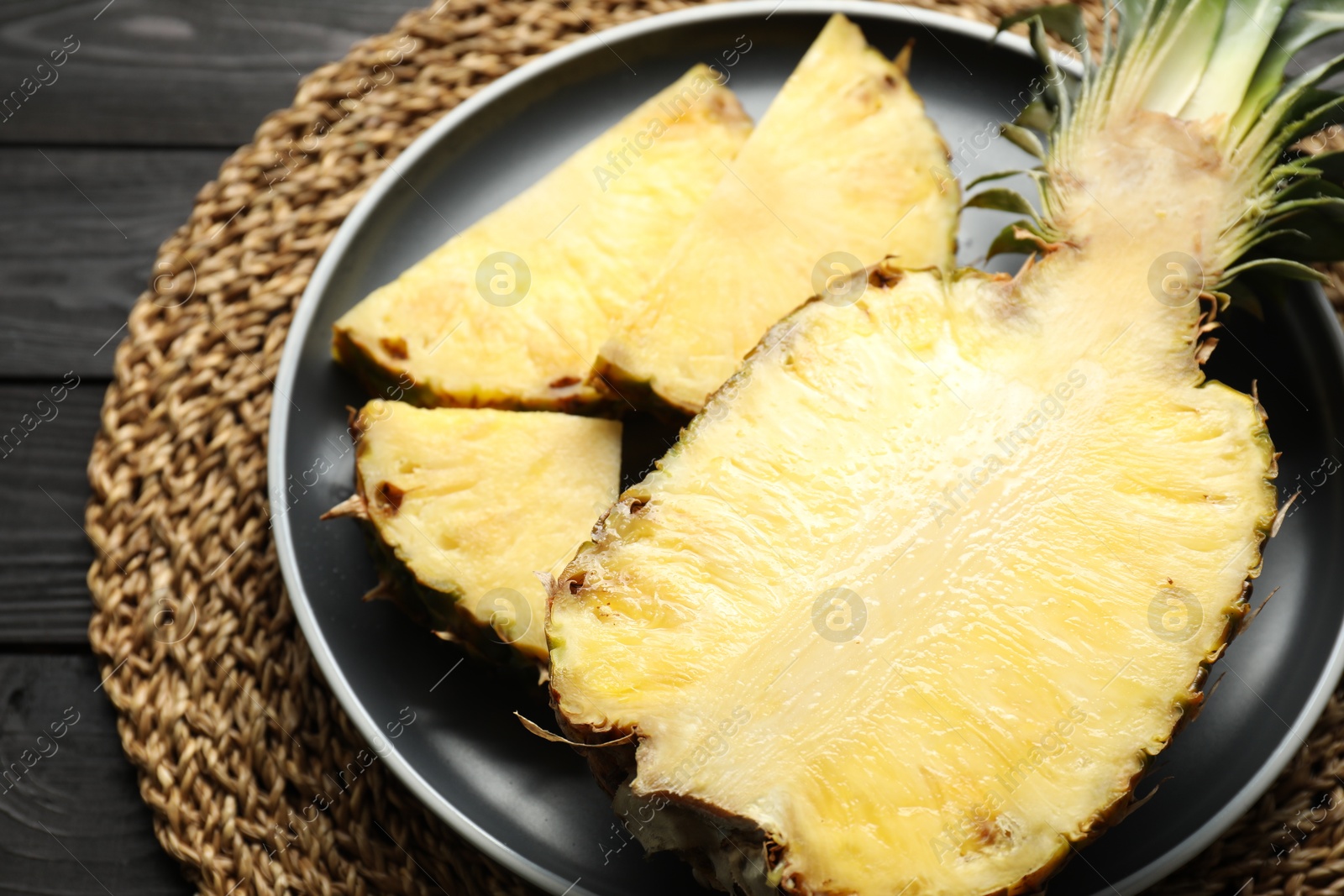 Photo of Cut fresh ripe pineapple on black wooden table, closeup