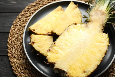 Cut fresh ripe pineapple on black wooden table, closeup