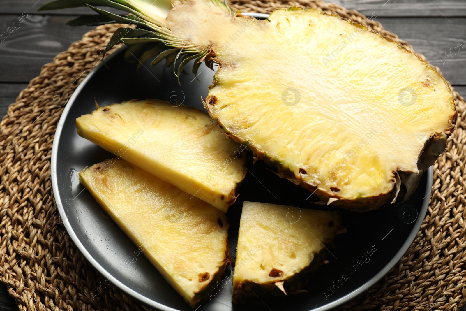 Photo of Cut fresh ripe pineapple on black wooden table, closeup