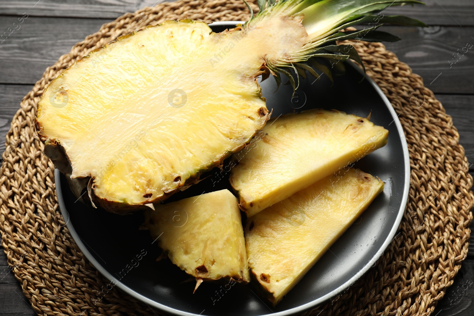 Photo of Cut fresh ripe pineapple on black wooden table, closeup