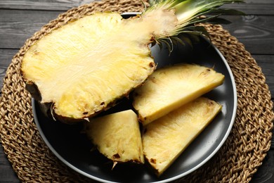 Cut fresh ripe pineapple on black wooden table, closeup