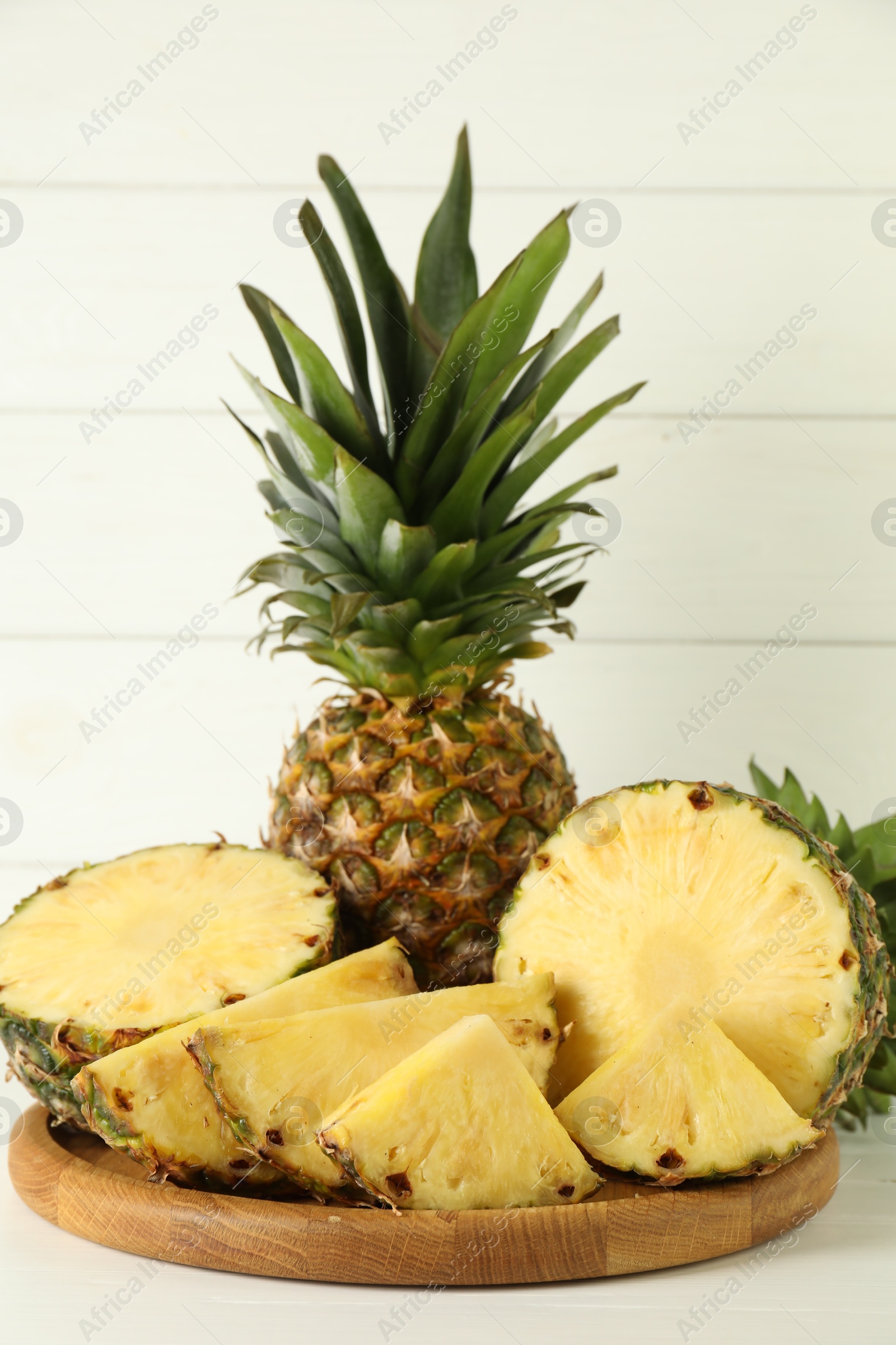 Photo of Whole and sliced fresh ripe pineapples on white table