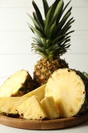 Whole and sliced fresh ripe pineapples on white table