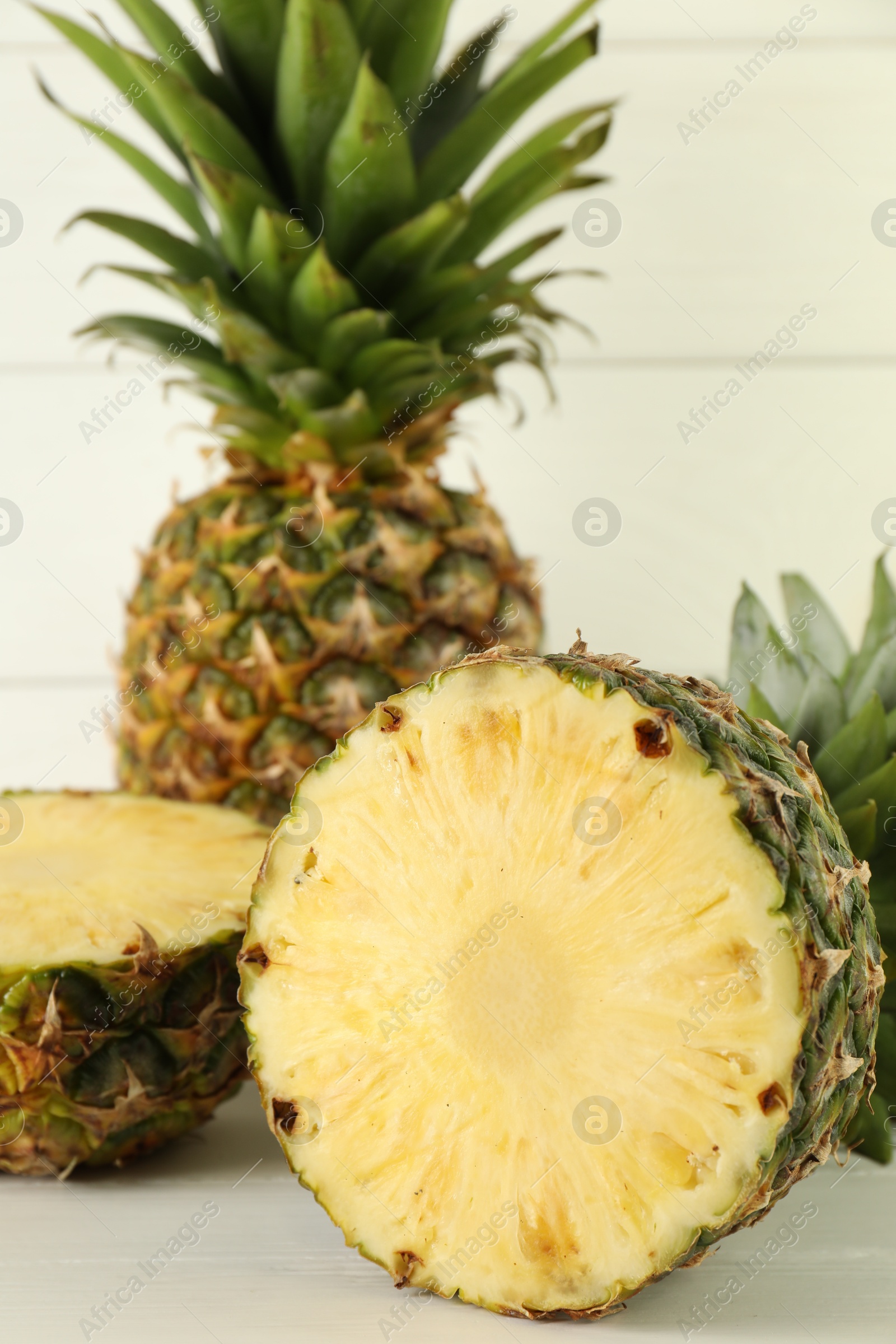 Photo of Whole and sliced fresh ripe pineapples on white wooden table