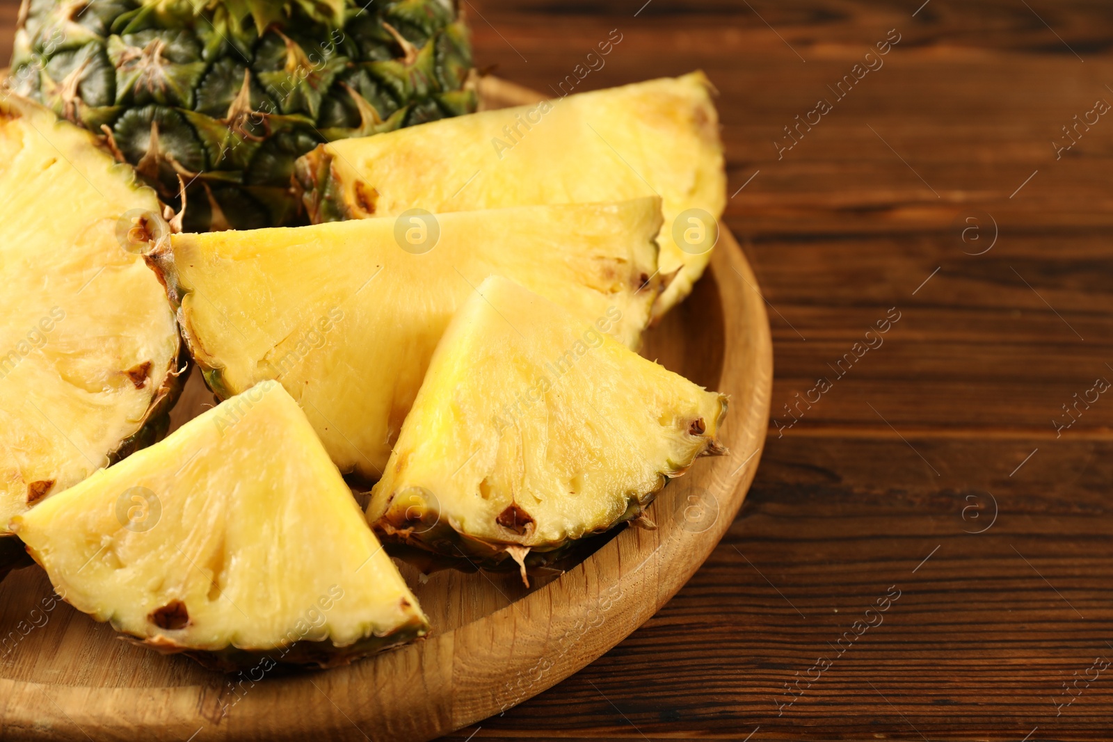 Photo of Cut fresh ripe pineapple on wooden table, closeup. Space for text