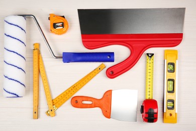 Different construction tools on light wooden table, flat lay